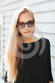 Stylish beautiful woman in sunglasses near a wooden wall