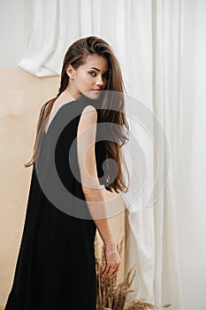 Stylish beautiful woman wearing a black V-neck dress looking over her shoulder