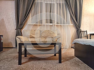 Stylish bedroom in beige tones and colors with double bed, sofa and table. Concept of cozy bedroom, living room or hotel