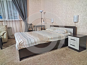 Stylish bedroom in beige tones and colors with double bed, sofa and table. Concept of cozy bedroom, living room or hotel