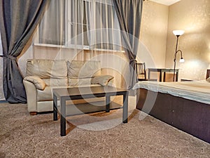 Stylish bedroom in beige tones and colors with double bed, sofa and table. Concept of cozy bedroom, living room or hotel