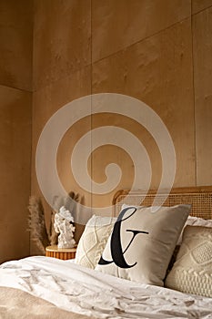 Stylish Bedroom corner with rattan headboard bed and soft pillow decoration with  with plywood wall on the background / cozy