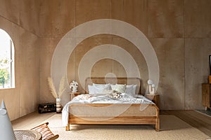 Stylish Bedroom corner with rattan headboard and bed with soft pillows setting with white pillows plywood wall on the background