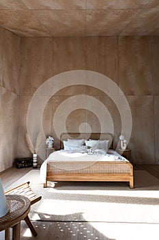 Stylish Bedroom corner with rattan headboard and bed with soft pillows setting with white pillows plywood wall on the background