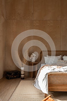 Stylish Bedroom corner with rattan headboard and bed with soft pillows setting with white pillows plywood wall on the background