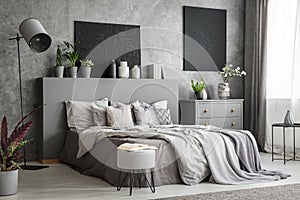 Stylish bedroom interior in grey with a big bed with bedsheets,