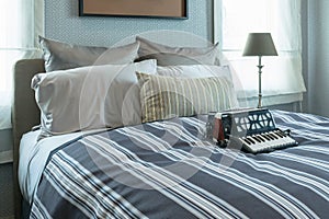 Stylish bedroom interior with striped pillows and decorative accordion on bed