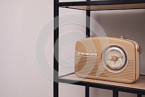 Stylish beige radio on rack near light wall indoors, space for text