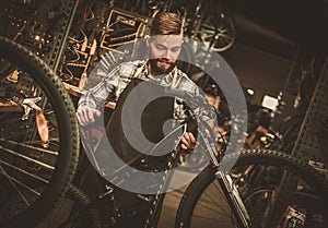Stylish bicycle mechanic doing his professional work in workshop.