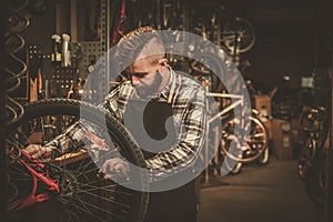 Stylish bicycle mechanic doing his professional work in workshop