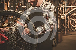 Stylish bicycle mechanic doing his professional work in workshop.