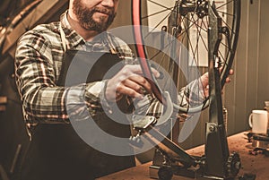 Stylish bicycle mechanic doing his professional work in workshop.
