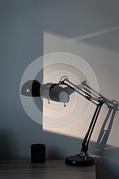 Stylish black lamp from Ikea on the wooden table with sun reflect on the background photo