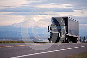 Stylish black modern powerful truck with black trailer scenic road