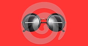 Stylish black round sunglasses isolated on red background