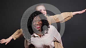 Stylish black stepmother holds adopted schoolgirl on backs