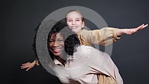 Stylish black stepmother holds adopted schoolgirl on backs