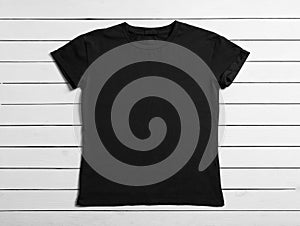 Stylish black t-shirt on white wooden background, top view