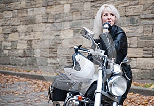Stylish blond woman posing with motorcycle.