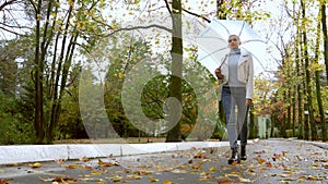 Stylish blond woman with short hair walks in the Park with umbrella