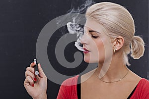 Stylish blond woman smoking an e-cigarette