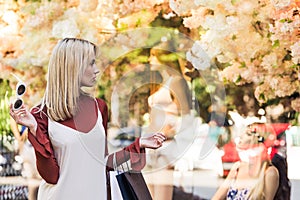 stylish blonde girl holding paper bags and looking at dummies