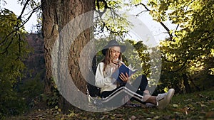 Stylish blonde hair woman relaxing in the park and reading book.