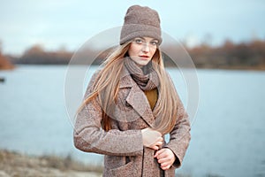 Stylish blonde woman in trendy urban outwear posing cold weather on the river bank. Vintage filter film saturated color. Fall mood