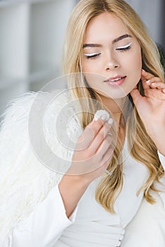 stylish blonde woman in fur coat eating