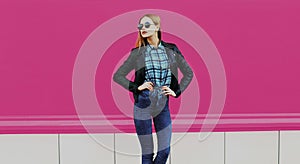Stylish blonde woman model wearing black rock style clothes over a pink background