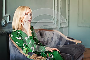 Stylish blonde woman sitting on sofa at home