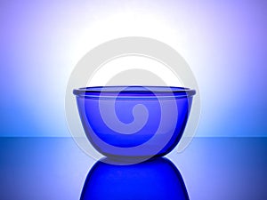 Stylish blue glass dinnerware on glowing gradient background for chic culinary presentation