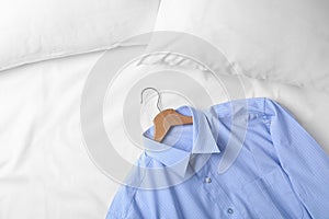 Stylish blue shirt on bed, space for text. Dry-cleaning service