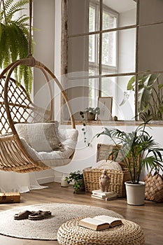 The stylish boho composition with changing swing, window, commode and wooden bench. Beige carpet with brown slippers. White wall.