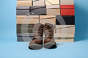 Stylish boots on the background of stacked shoe boxes. Shopping concept. Copy space.