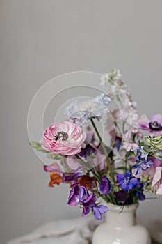 Stylish bouquet on rustic linen background. Beautiful colorful anemone, ranunculus, lathyrus scabiosa in vase. Summer flowers,