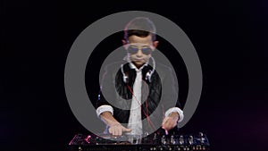 Stylish boy dj with glasses playing on vinyl. Black background