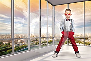 Stylish boy in fashionable clothes and sunglasses from the sun in the office. Children`s fashion.