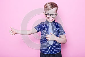 Stylish boy in shirt and glasses with big smile. School. Preschool. Fashion. Studio portrait over pink background