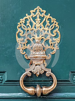 Stylish brass doorknocker on green wooden door