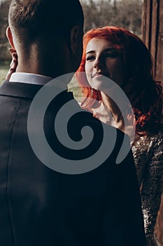 Stylish bride and groom hugging in light on background of wooden wall in barn. rustic wedding concept, space for text. happy