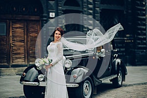 stylish bride and groom sensually posing near retro car with boh