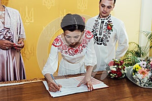 Stylish bride and groom, signing official wedding register