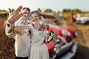 Stylish bride and happy groom near car on the background of nature and friends bridesmaids