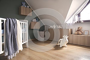 Stylish and bright scandinavian decor of newborn baby room with white design furnitures, natural toys, accessories and teddy bears