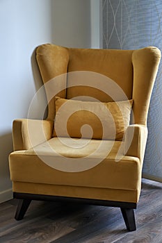 Stylish bright yellow chair. Chair in room with ears and armrest. Classic style.
