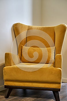 Stylish bright yellow chair. Chair in room with ears and armrest. Classic style.