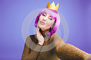 Stylish brightful selfie portrait fashionable young woman celebrating party on violet background. Cut purple hair