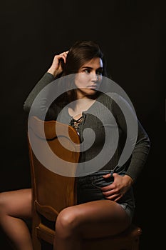 Stylish brunette girl sitting in studio during model tests, dressed in grey underwear and jeans shorts