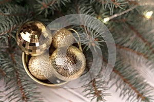 Stylish bucket of Christmas Golden toys on a white wooden background and branches of Christmas trees